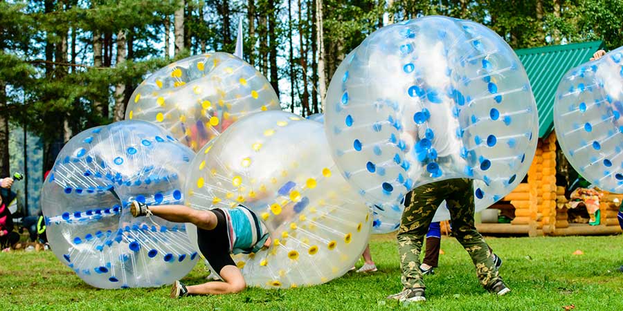 Vier Menschen in großen Plastikbällen spielen den Outdoor Trend Bubble Football