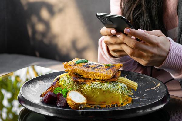 Frau fotografiert ihr gesundes Mittagessen mit Handy
