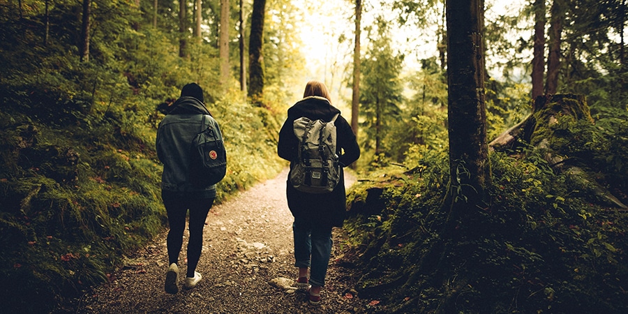 2 Personen laufen warm angezogen durch den Wald