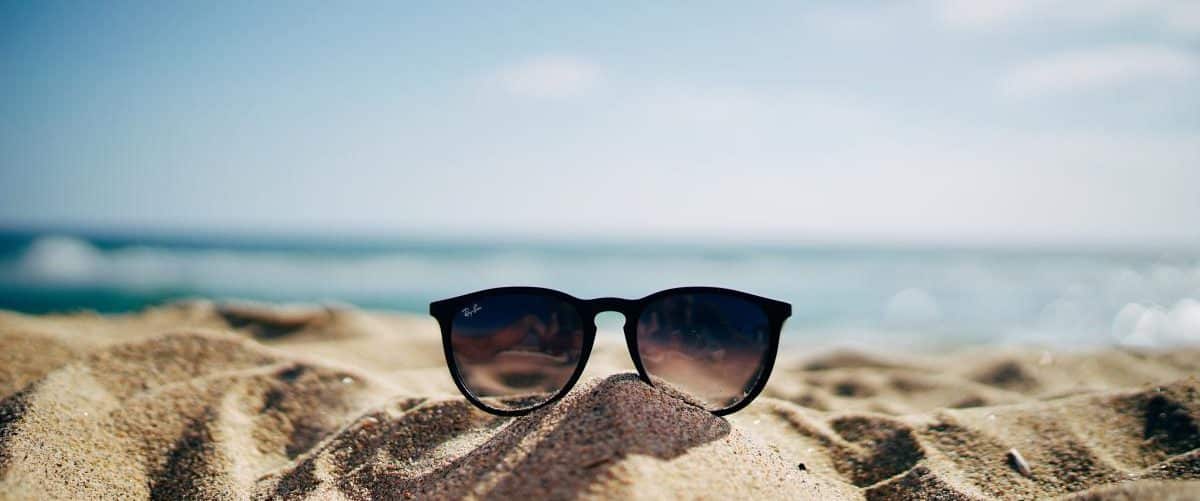 Sonnenbrille liegt am Strand auf einem kleinen Sandhaufen