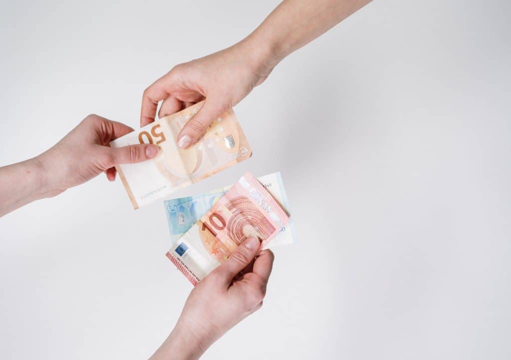 Geldscheine werden von einer Hand in eine andere übergeben - Symbolbild für Kosten für ein Studium