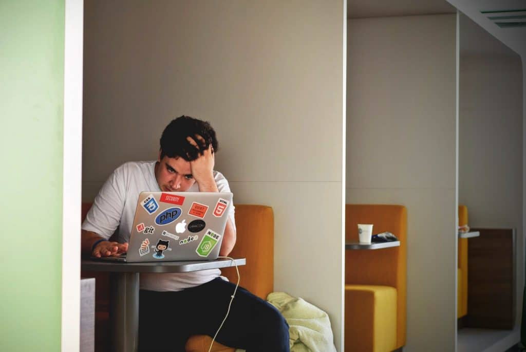 Junger Mann sitzt in einem Café vor seinem Laptop und lernt für Prüfungen - Symbolbild für Prüfungs- und Lerntipps